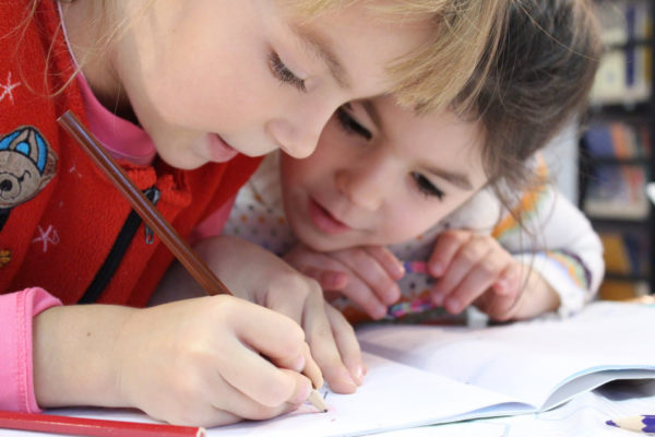 two young girls studying a book