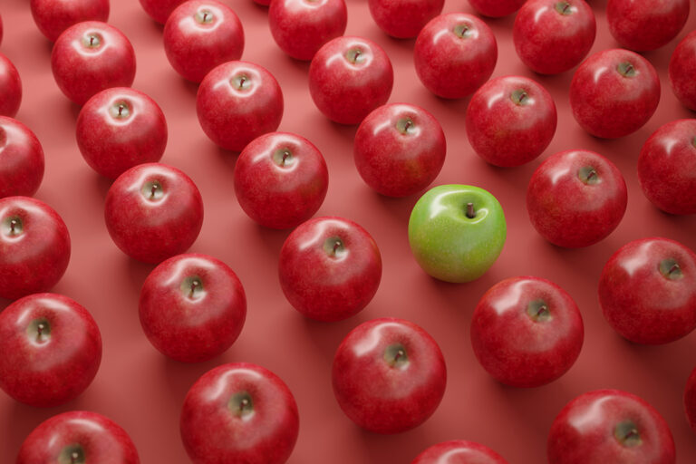 lots of red apples lined up with one green apple standing out